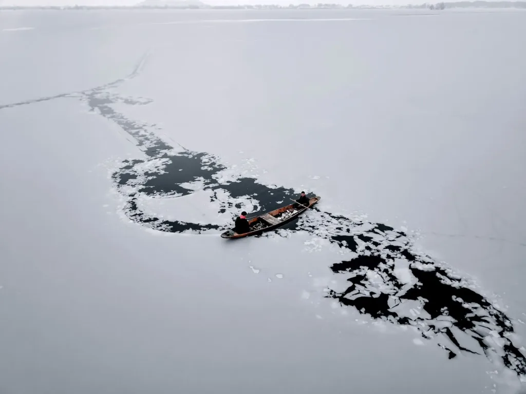 A boat breaking a path through the frozen Dal Lake in Srinagar in winter